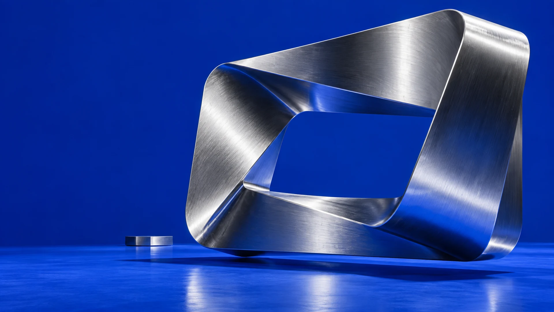 A sculptural aluminum ribbon suspended against a vivid cobalt-blue backdrop